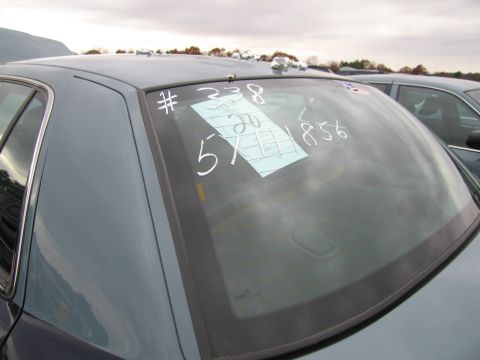 1991 Ford LTD Crown Victoria - A car's rear window displays a paper tag and handwritten markings, possibly for inventory or sale.