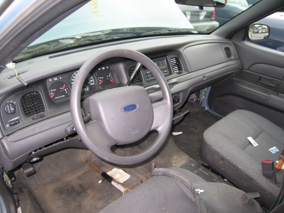 Car interior with Ford steering wheel, dashboard, and seats. Hood is open