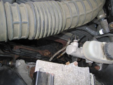 1991 Ford LTD Crown Victoria - Close-up view of the brake master cylinder and air intake hose within the engine bay.