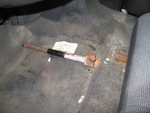 1991 Ford LTD Crown Victoria - A rusty driveshaft component lies on the floor of a vehicle, next to a crumpled paper towel and scattered hardware.
