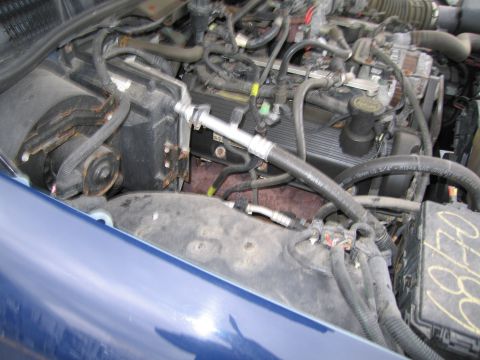 1991 Ford LTD Crown Victoria - Engine bay detail showing AC lines and hoses, with a blue fender in the foreground.