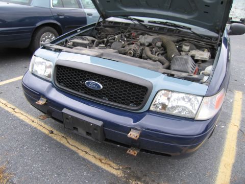 1991 Ford LTD Crown Victoria - The front of a Ford Crown Victoria is shown with its hood up, revealing the engine compartment.