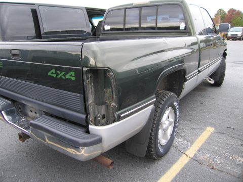 1991 Ford LTD Crown Victoria - A green and silver pickup truck is parked next to another vehicle, showing its rear end with a missing taillight.