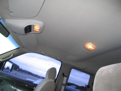 1991 Ford LTD Crown Victoria - The interior ceiling of a vehicle shows two illuminated dome lights and a visor.