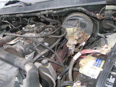 1991 Ford LTD Crown Victoria - A view of the engine bay, showing the brake booster, master cylinder, and battery, with various hoses and wiring.