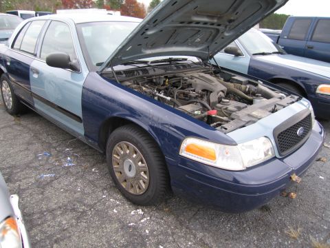 1991 Ford LTD Crown Victoria - A Ford Crown Victoria is parked with its hood up, revealing the engine compartment and a two-tone paint scheme.