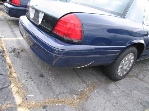 1991 Ford LTD Crown Victoria - Rear view of a blue sedan with visible damage to the bumper and taillight assembly.