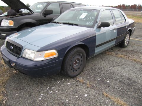 1991 Ford LTD Crown Victoria - A two-tone Ford Crown Victoria is parked next to a black SUV with its hood open.