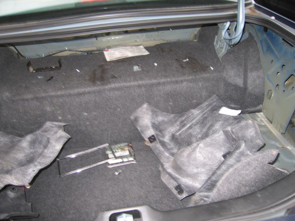 Car trunk with carpet removed, showing wiring and some components