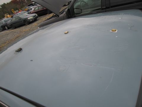 1991 Ford LTD Crown Victoria - The roof of a gray car shows three circular mounts and visible scratches, with other vehicles and equipment in the background.