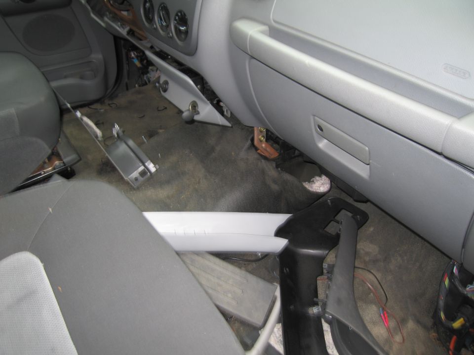 Interior of a car with dashboard disassembled, showing exposed wires and parts on the floor