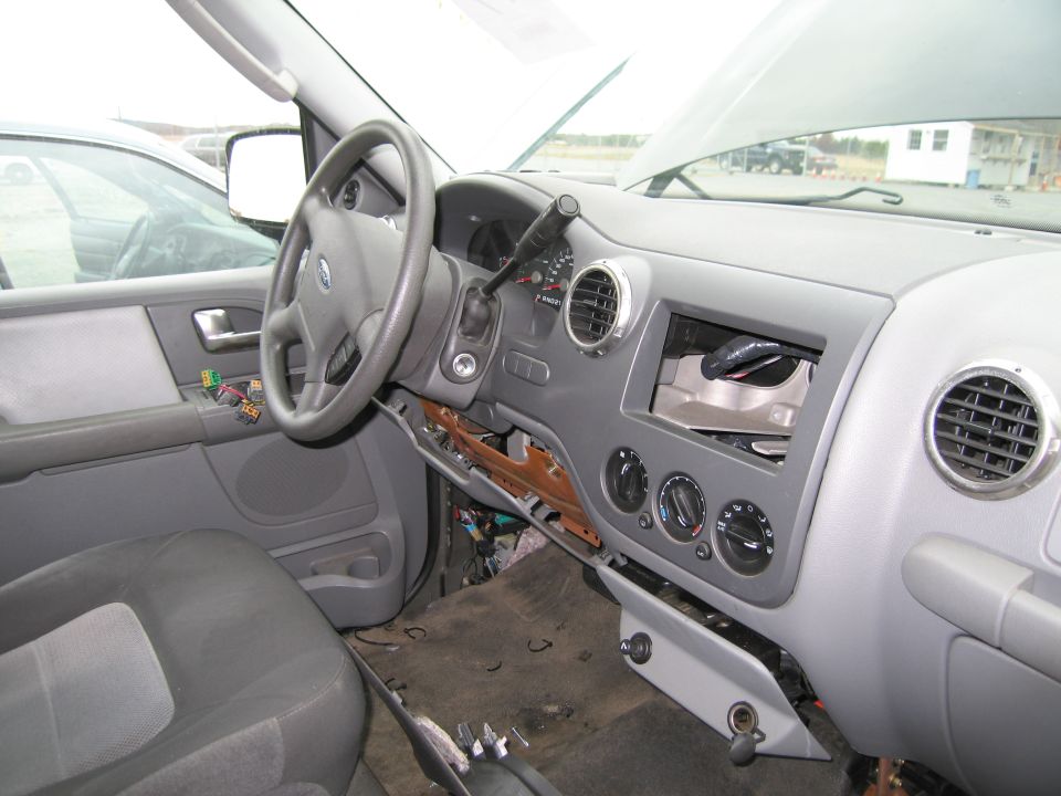 Interior of a Ford SUV with the dashboard partially disassembled. Wires are exposed under the dash