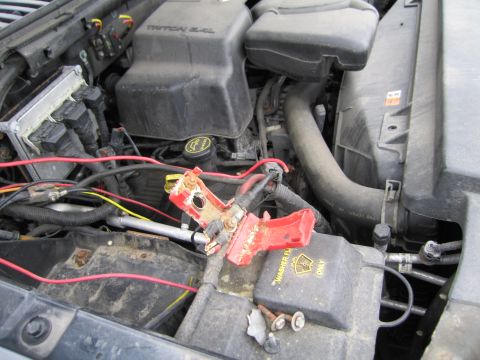 1991 Ford LTD Crown Victoria - Close-up of a vehicle's engine bay, showing battery terminals and associated wiring, with a warning label for washer fluid.