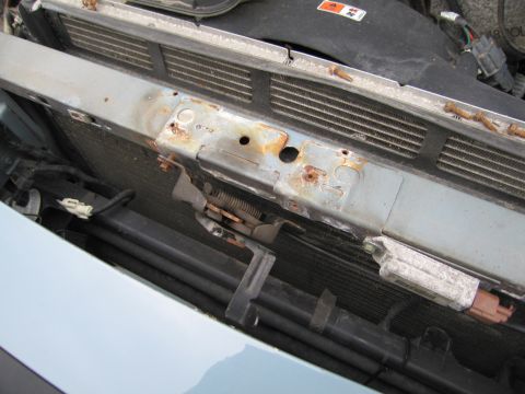 1991 Ford LTD Crown Victoria - Close-up view of the engine bay radiator support, showing signs of rust and exposed electrical components.
