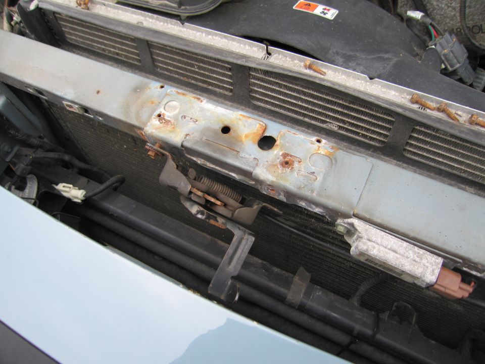 Engine bay radiator support with rust and visible wiring