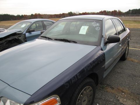 1991 Ford LTD Crown Victoria - A light blue and dark blue police car is parked in a lot next to another damaged vehicle.