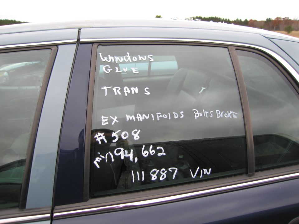 Dark blue sedan side window with handwritten notes: Windows Glue, Trans, Ex Manifolds Bolts Broke, #508, 194,662, 111887 VIN