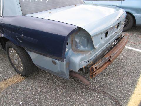1991 Ford LTD Crown Victoria - The rear of a car, missing its bumper and taillights, is shown with a second vehicle in the background.