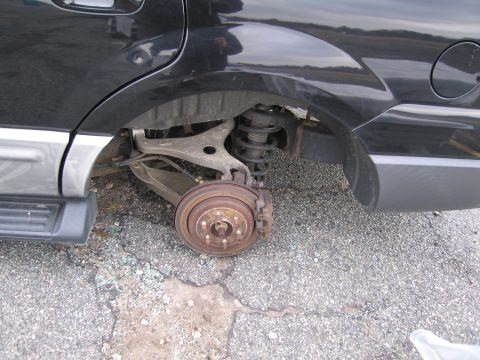1991 Ford LTD Crown Victoria - The rear suspension and brake rotor of a black SUV are visible, with the wheel missing.