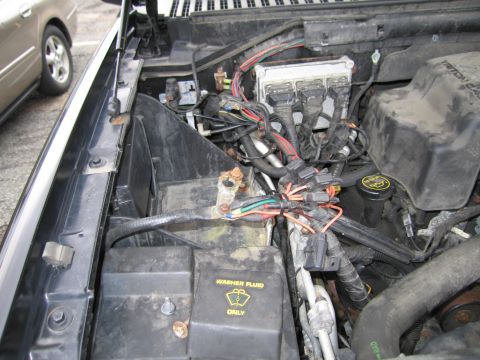 1991 Ford LTD Crown Victoria - The engine bay shows a complex network of wiring and the battery, with a washer fluid reservoir clearly marked.