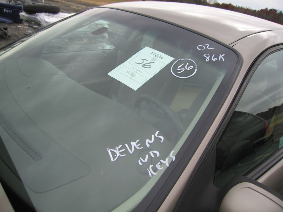 Car interior showing dashboard, steering wheel, and windshield with item tags and handwritten notes