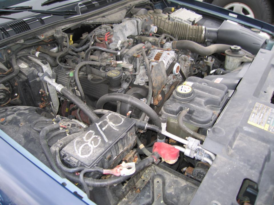 Engine bay of a blue 1991 Ford Crown Victoria LTD, showing the engine, hoses, battery, and fuse box with handwritten "68FC"