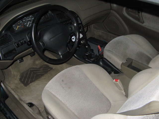 Car interior with black steering wheel, dark dash, and beige cloth seats