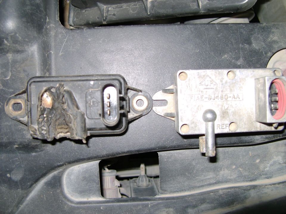 Burned black plastic DPFE sensor beside an aluminum F1AE-9J460-AA sensor on an engine cover