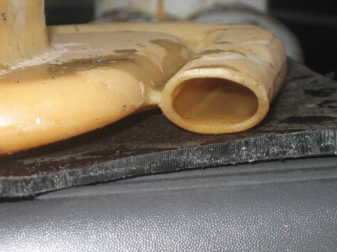 1996 Ford Thunderbird - Close-up view of a beige plastic hose and a black gasket, likely a vehicle part.