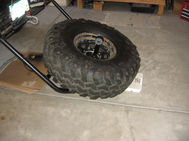 Off-road mud tire on chrome wheel sitting on a balancer in a garage
