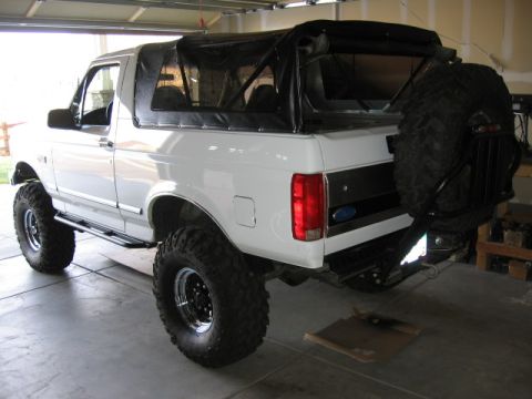 1995 Ford Bronco - This 1995 Ford Bronco features a soft top and a spare tire mounted on a drop-down carrier at the rear.