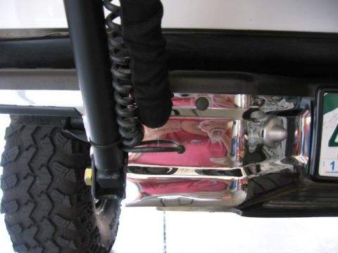 1995 Ford Bronco - Detail of a vehicle's rear bumper and tire carrier mount, showing chrome accents and a tire.
