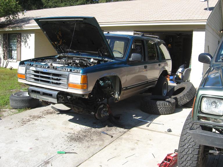 1992 Ford Explorer with hood open, front end raised on jack stands, tires removed