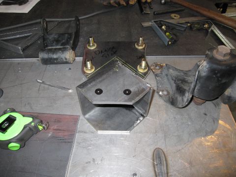 1996 Ford Bronco - Metal bracket components are laid out on a workbench with tools and a tape measure.