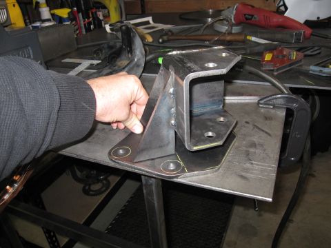 1996 Ford Bronco - Custom metal bracket with mounting holes, held by a hand on a workbench.
