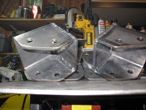 1996 Ford Bronco - These metal shackle flip brackets are shown in a workshop setting, ready for installation.