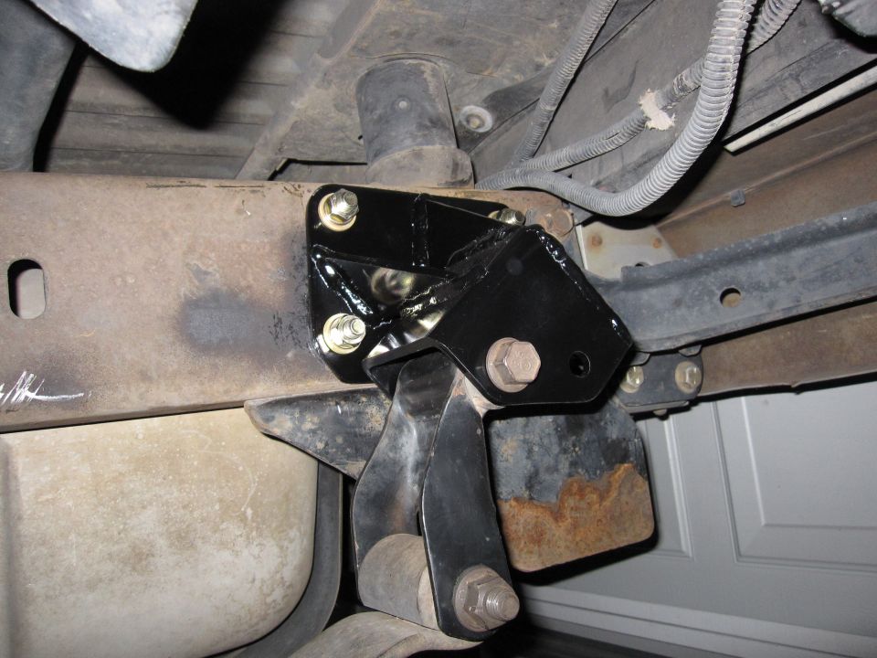 Black welded suspension bracket bolted to a vehicle frame rail