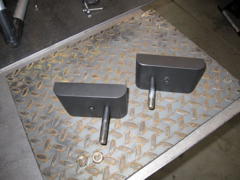 Two metal blocks with bolts on diamond plate surface