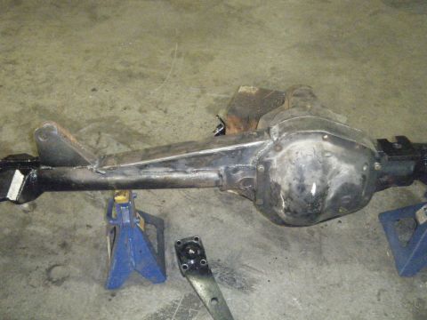 1978 Ford Bronco - A rear axle assembly is shown supported by jack stands, with a separate metal bracket visible on the floor.