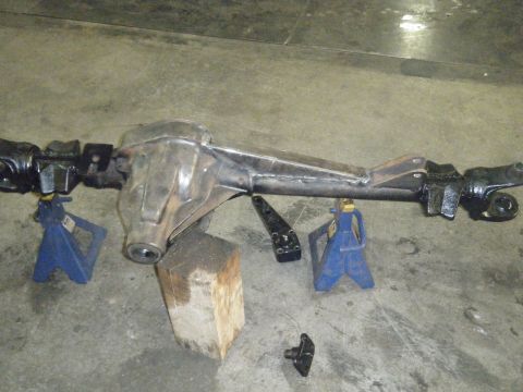 1978 Ford Bronco - A vehicle's rear axle assembly is supported by jack stands on a concrete floor.
