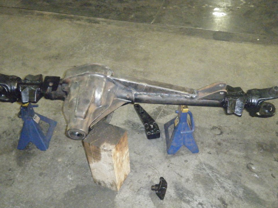 rear axle assembly on jack stands, with a wooden block and some brackets nearby