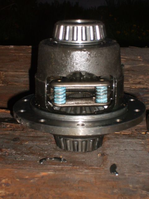 1989 Ford Bronco - A differential carrier sits on a wooden surface, showing internal gears and springs.