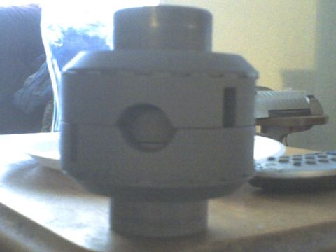 1989 Ford Bronco - A gray cylindrical part with distinct circular and rectangular openings is shown in close-up.