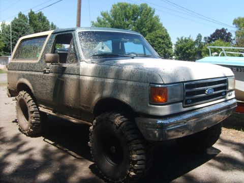 1989 Ford Bronco - This 1989 Ford Bronco is heavily covered in mud, indicating recent off-road use.