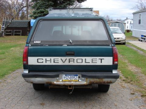 1984 Ford F-250 - Rear view of a teal Chevrolet truck with a Leer cap, parked next to a silver car.