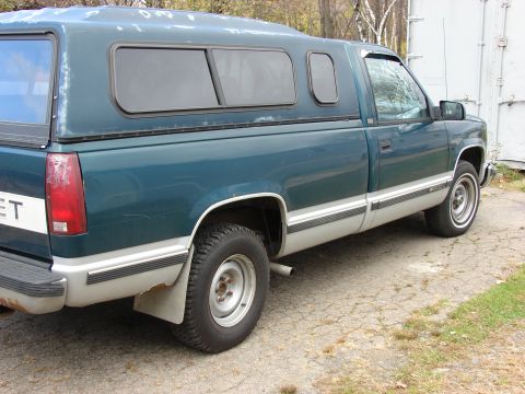 1984 Ford F-250 - This teal pickup truck, likely from the 1990s, is viewed from the side and features a camper shell.
