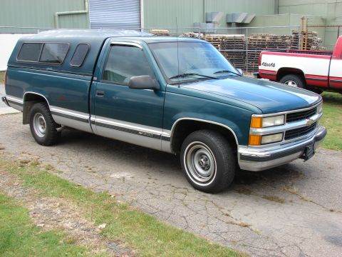 1984 Ford F-250 - This pickup truck features a two-tone paint scheme and a camper shell, with another truck in the background.