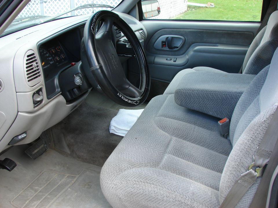 Gray cloth interior of a Chevrolet truck, showing dashboard, steering wheel, and front seats