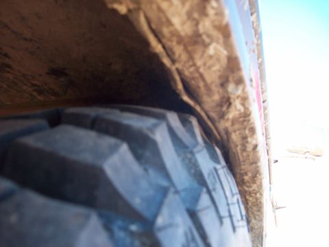 1985 Ford Bronco - A close-up view of a tire and its wheel well shows dirt and wear.