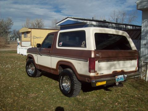 1985 Ford Bronco - This two-tone 1985 Ford Bronco is parked on a grassy lawn with a mobile home in the background.